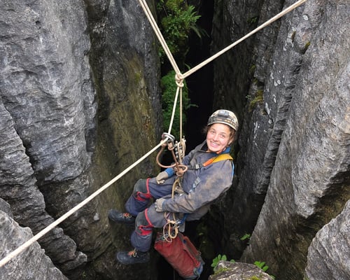 Caver at the top of a pothole, abseiling down a rope
