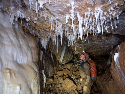 A caver looking at delicate formations in the White Forest