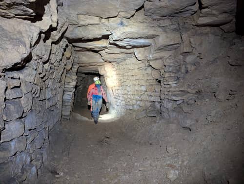 Two cavers walking through a passage in Windrush Stone Quarry